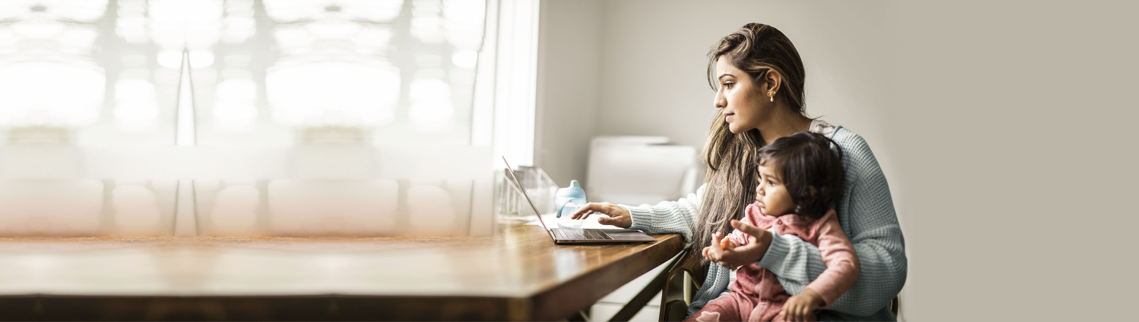 Women accessing her laptop along with a child in her lap